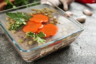 Photo of Delicious aspic with meat and vegetables served on grey table, closeup