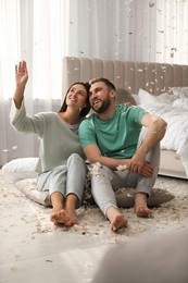 Photo of Happy young couple resting after fun pillow fight in bedroom