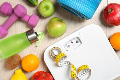 Photo of Flat lay composition with scales, healthy food and sport equipment on wooden background. Weight loss