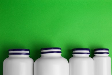 Photo of Medicine bottles on green background, flat lay. Space for text