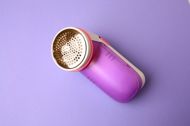 Modern fabric shaver on violet background, top view