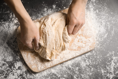 Woman with dough at grey table, top view. Making pasta