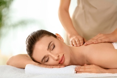 Photo of Beautiful young woman enjoying massage in spa salon