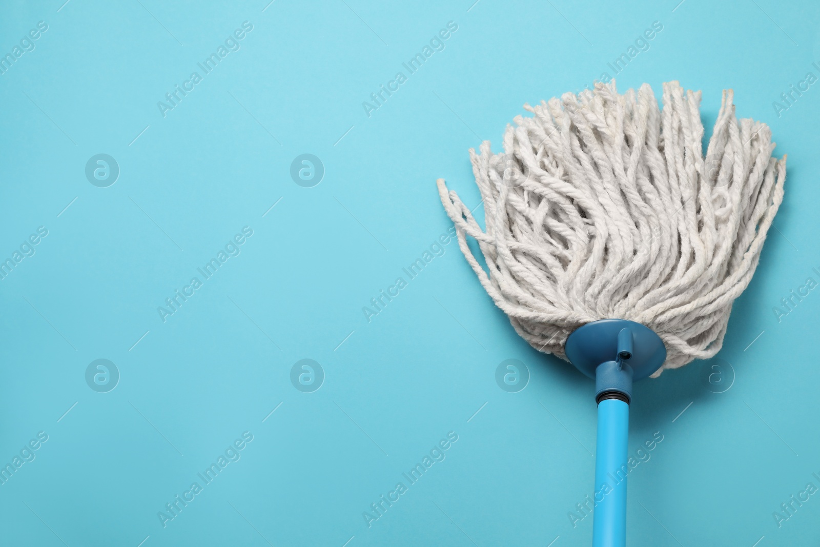 Photo of Mop with plastic handle on light blue background, top view. Space for text