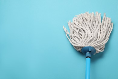 Photo of Mop with plastic handle on light blue background, top view. Space for text