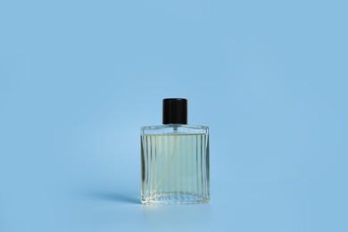 Photo of Bottle of fragrant perfume on light blue background