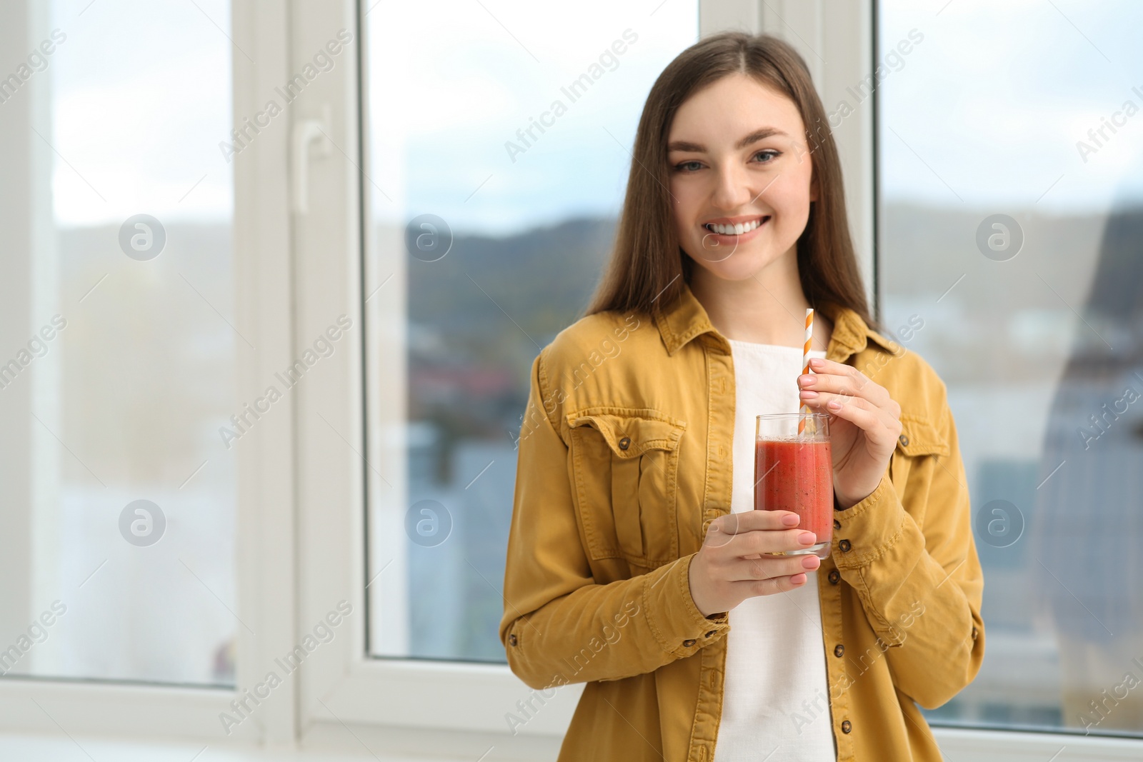 Photo of Beautiful young woman with delicious smoothie near window. Space for text