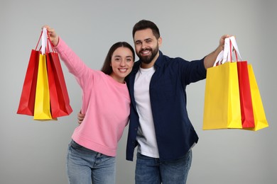 Happy couple with shopping bags on grey background