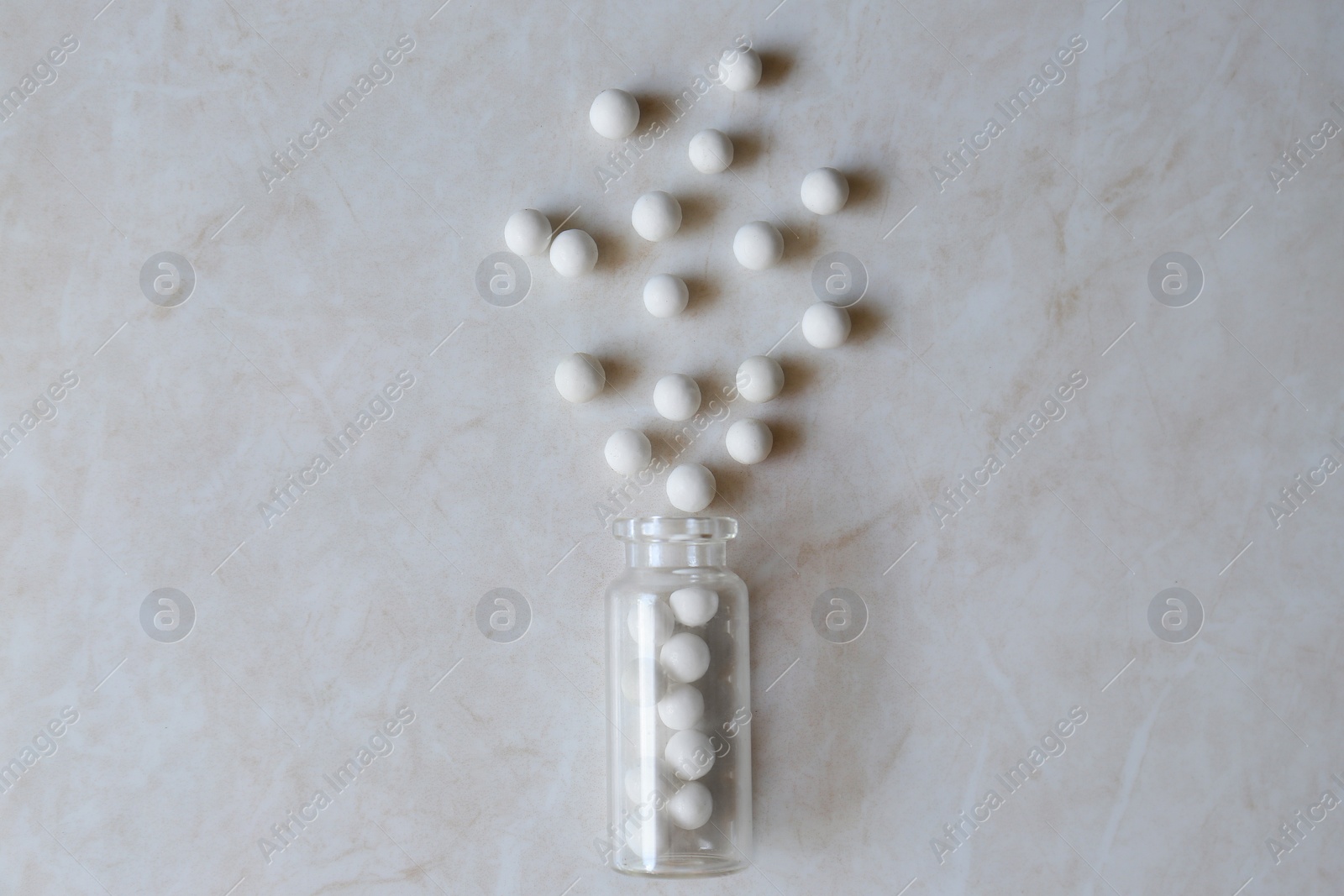 Photo of Bottle with homeopathic remedy on white table, flat lay