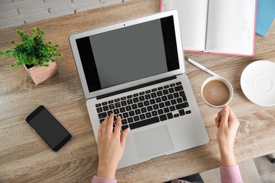 Woman using laptop at table, closeup. Space for design