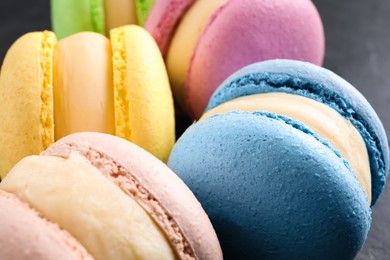 Photo of Delicious colorful macarons on black table, closeup