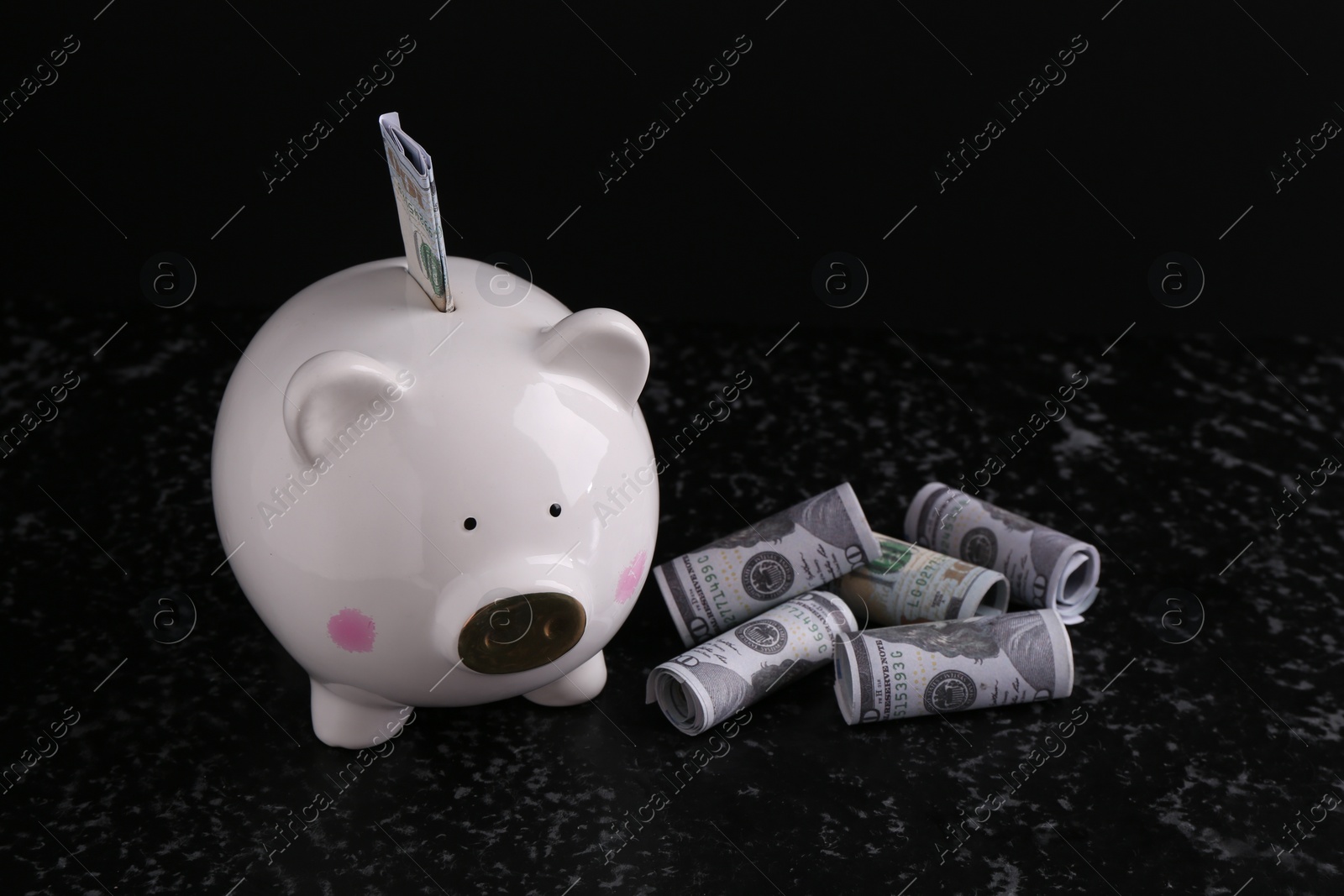 Photo of Financial savings. Piggy bank and dollar banknotes on black textured table