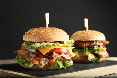 Photo of Tasty burgers with bacon served on board