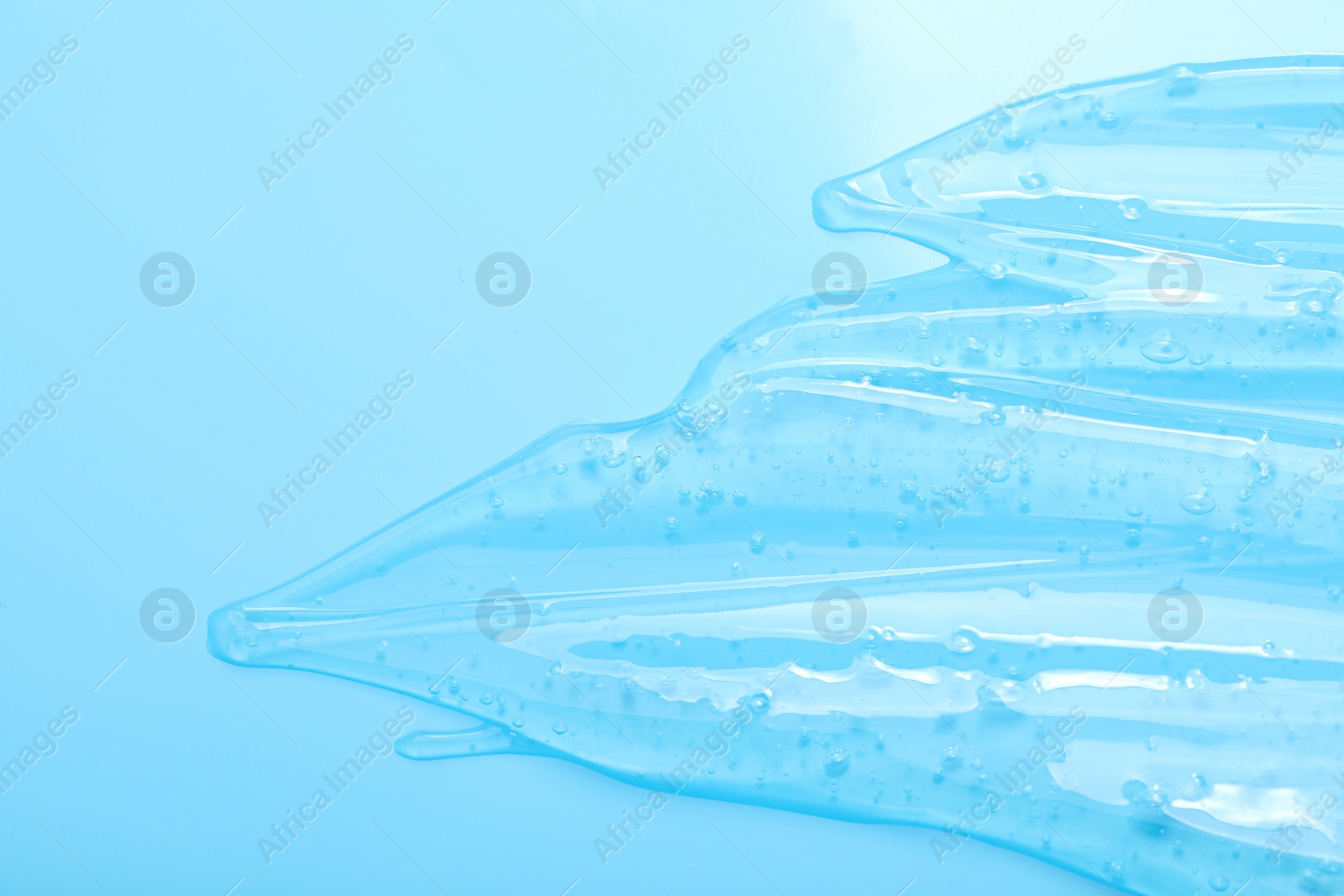 Photo of Pure transparent cosmetic gel on light blue background, top view