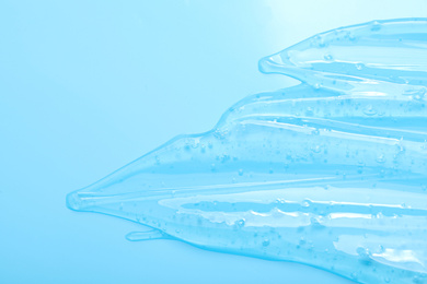 Photo of Pure transparent cosmetic gel on light blue background, top view
