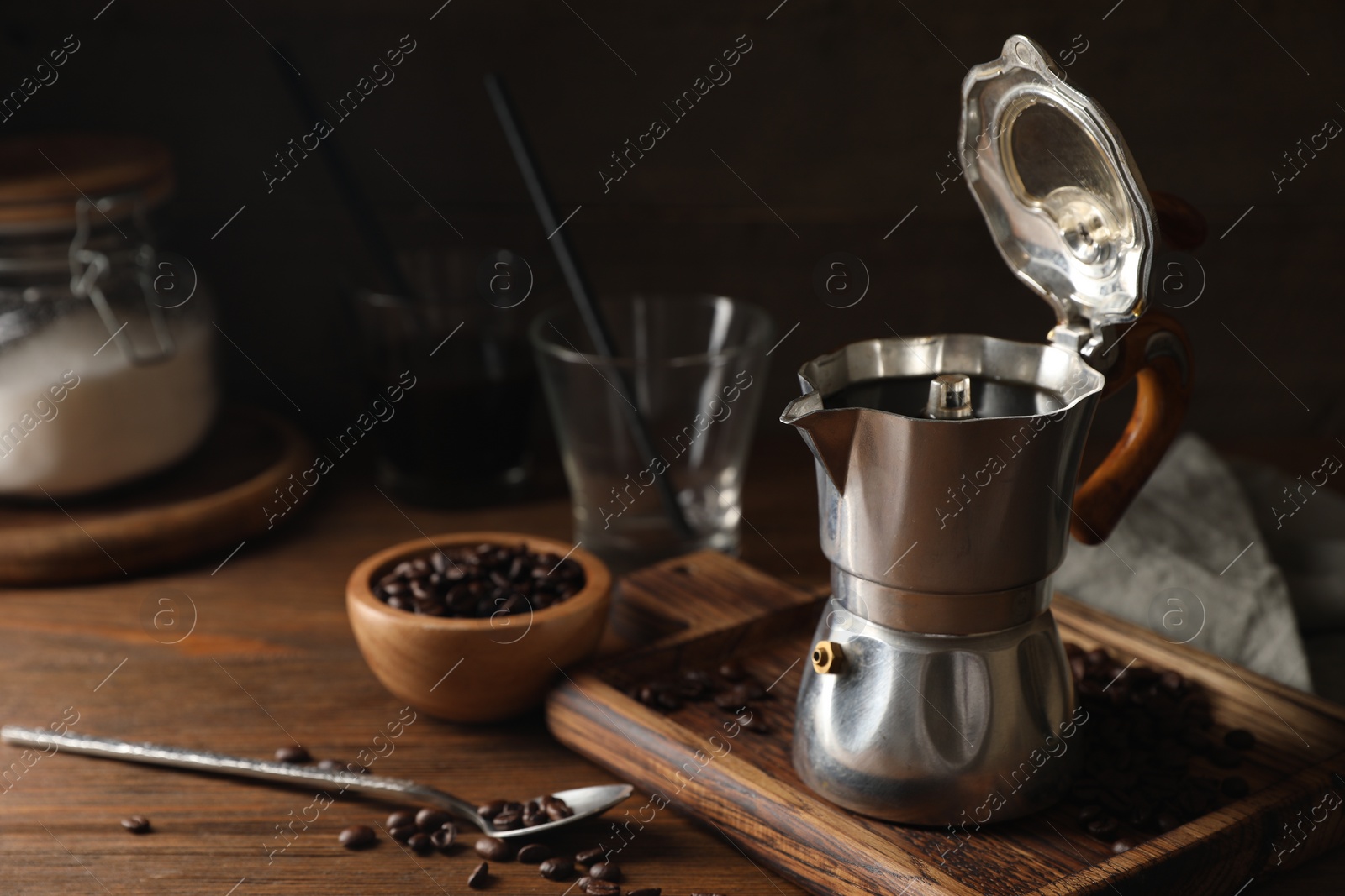 Photo of Brewed coffee in moka pot and beans on wooden table