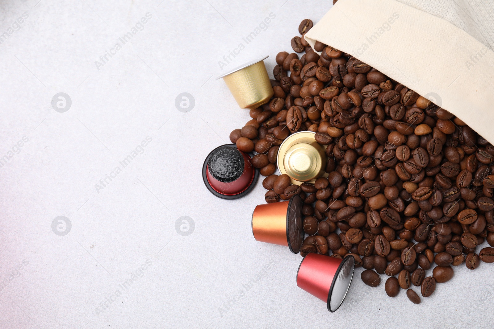 Photo of Bag with coffee capsules and beans on light grey table, top view. Space for text