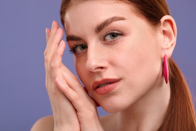 Portrait of beautiful woman with freckles on purple background, closeup