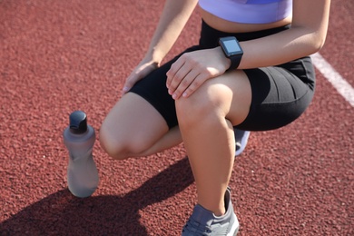 Woman with fitness tracker after training at stadium, closeup