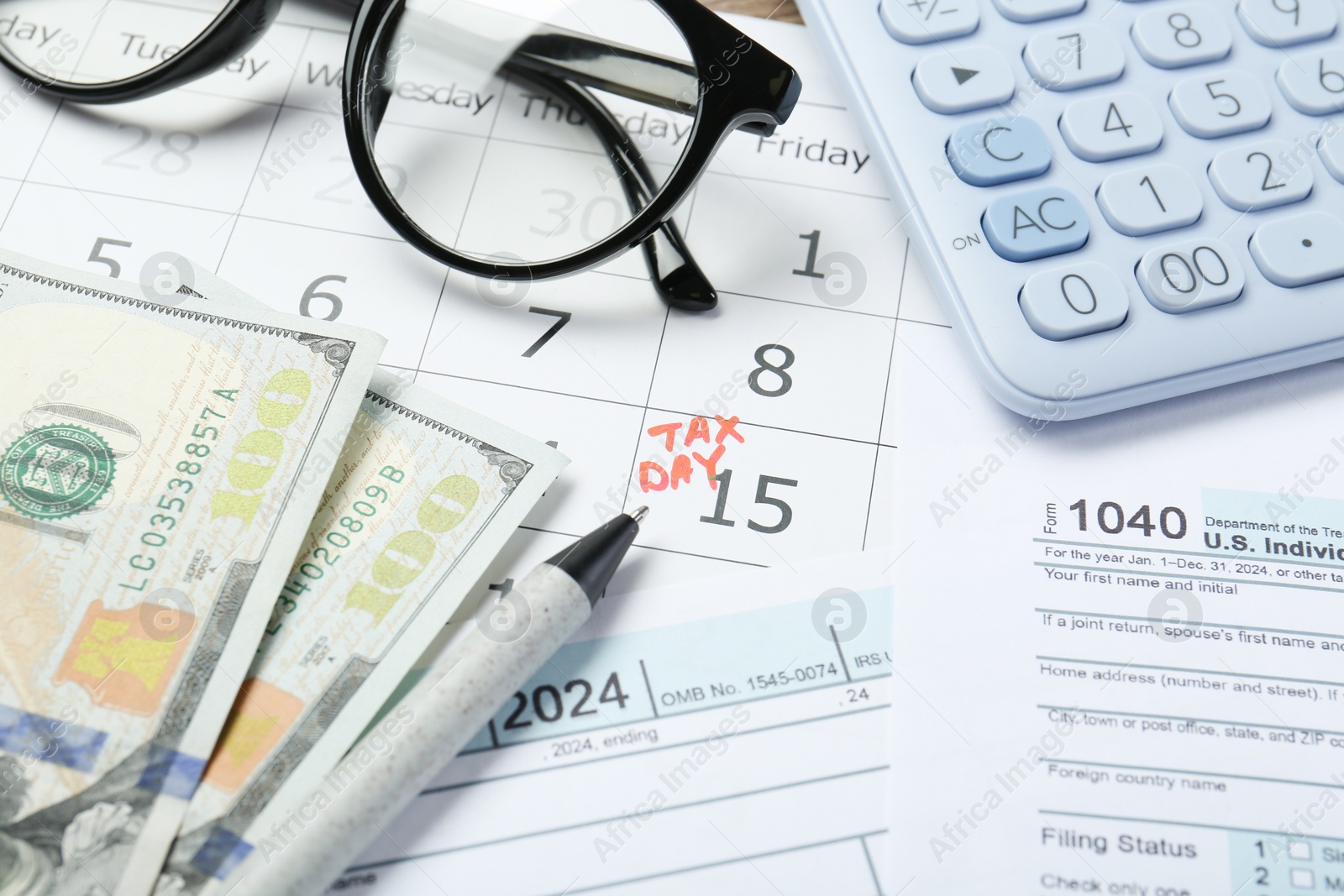 Photo of Calendar with date reminder about tax day, documents, money, pen, glasses and calculator, closeup