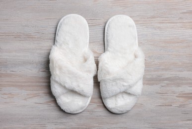 Photo of Pair of soft slippers on white wooden floor, top view
