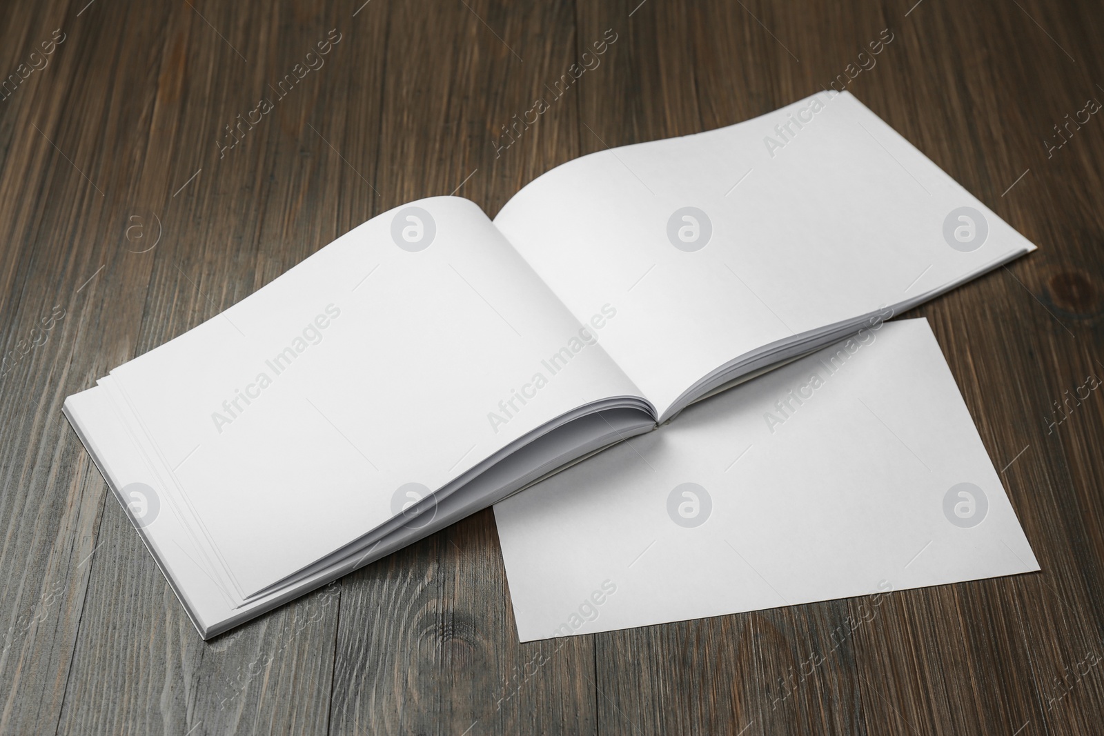 Photo of Sheet of paper and blank brochure on wooden table. Mockup for design