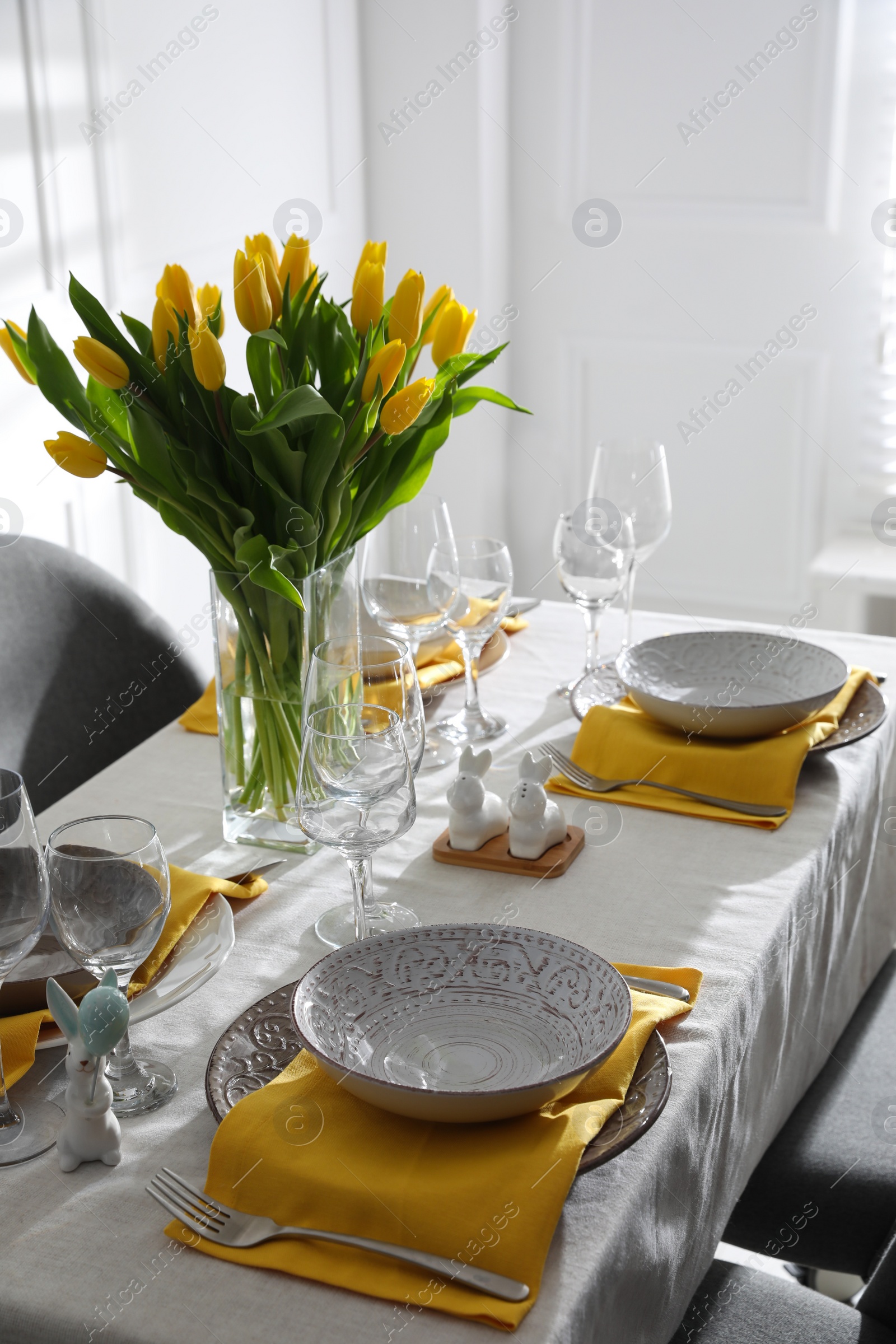 Photo of Beautiful Easter table setting with yellow tulips indoors