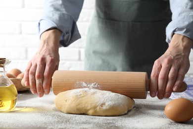 Photo of Woman rolling raw dough at table, closeup