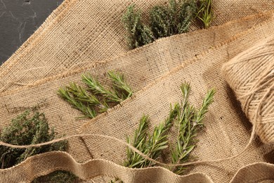 Photo of Natural burlap fabric, jute and fresh herbs on table, top view