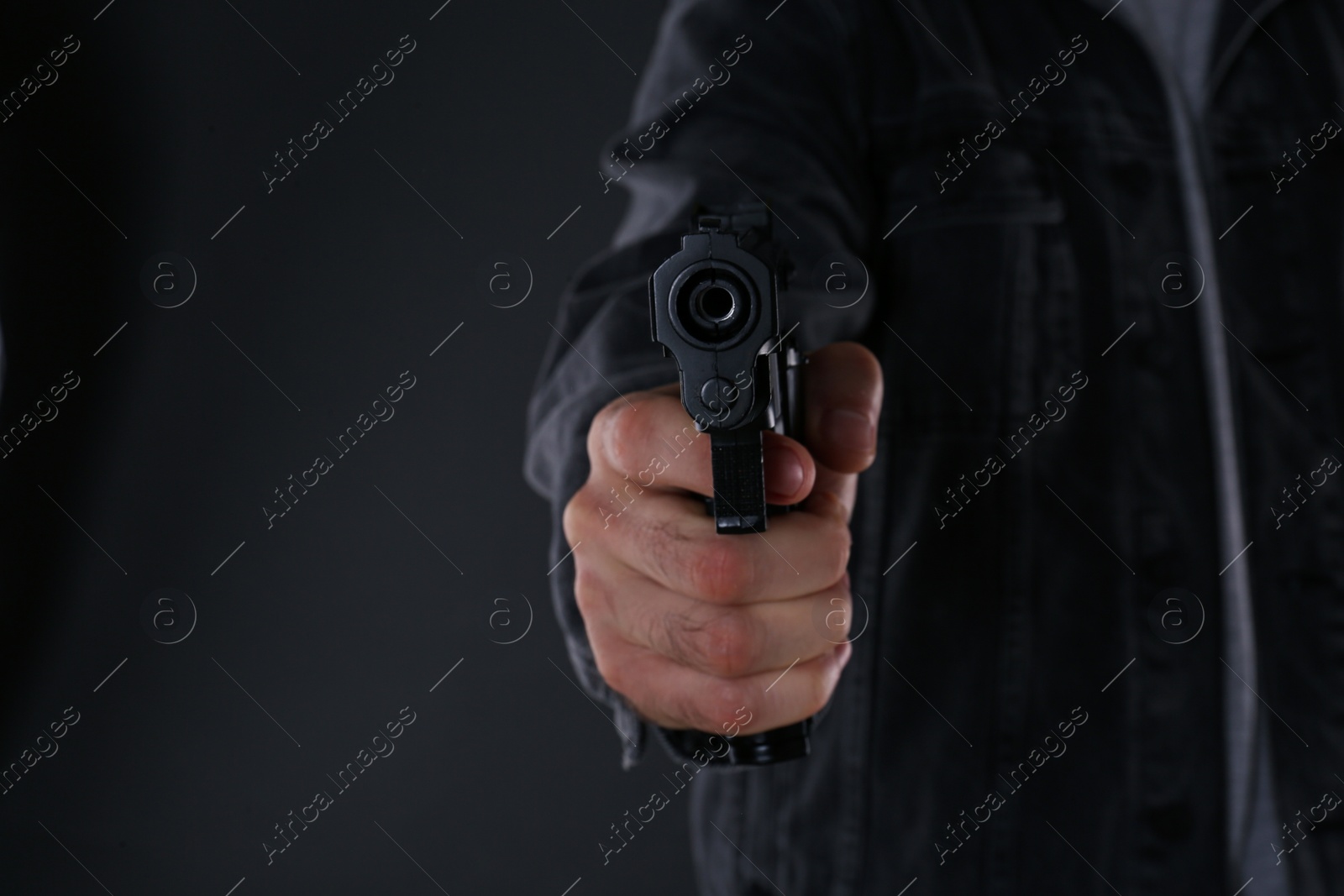 Photo of Man holding gun on black background, closeup