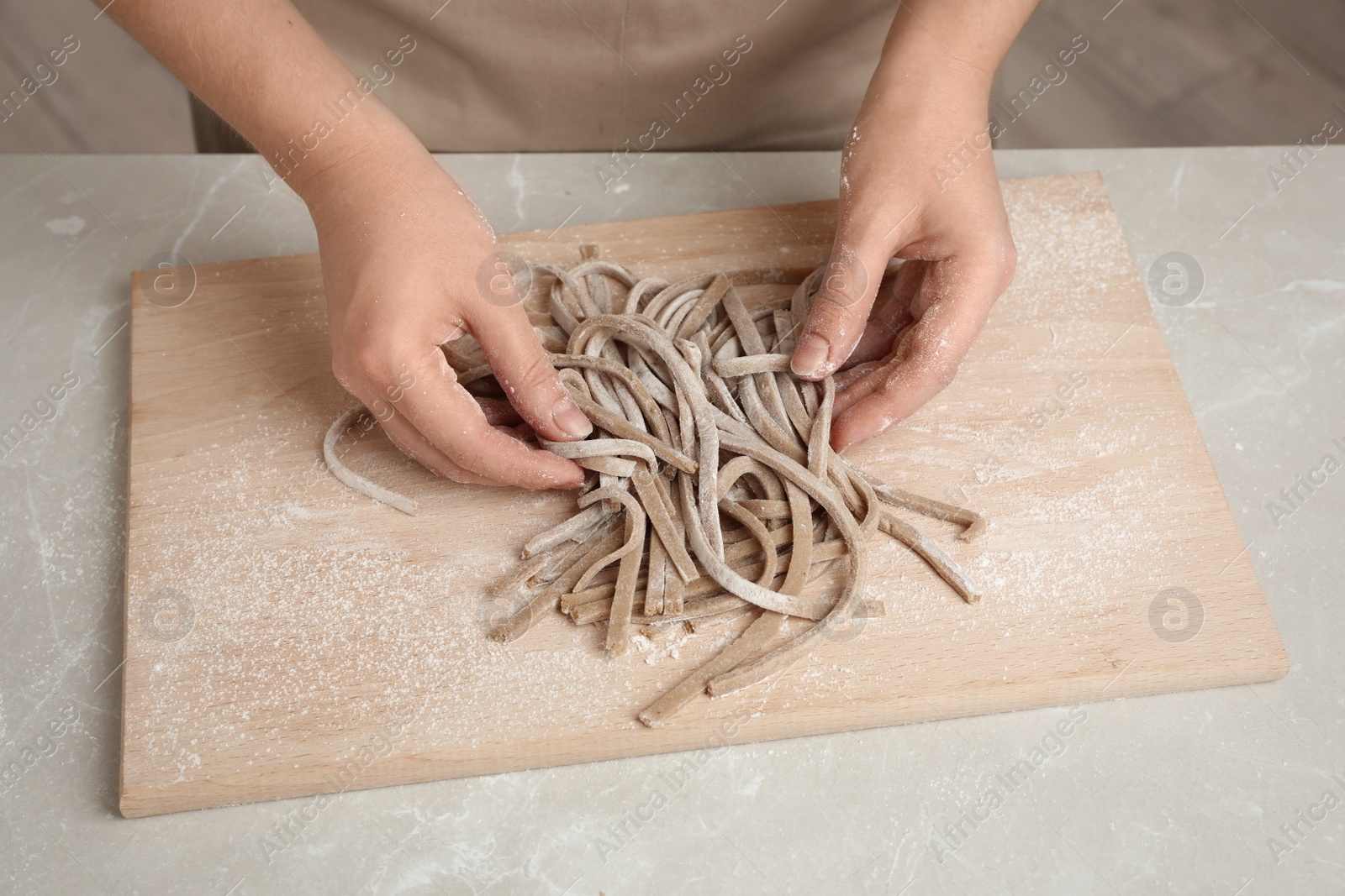 Photo of Woman with soba (buckwheat noodles) at light marble table, closeup