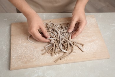 Woman with soba (buckwheat noodles) at light marble table, closeup