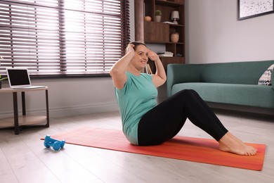 Overweight woman doing abs exercise on yoga mat at home, space for text