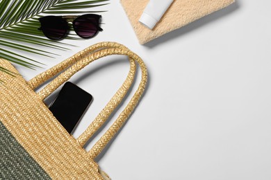 Photo of Flat lay composition with wicker bag, palm leaf and other beach accessories on white background. Space for text