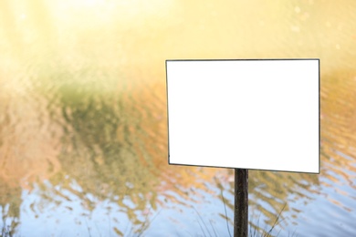 Empty sign board near pond. Space for text