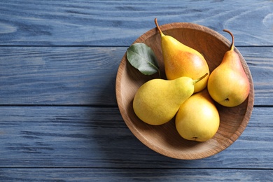 Plate with ripe pears on blue wooden background, top view. Space for text