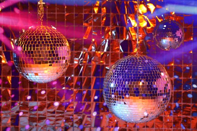 Photo of Shiny disco balls against foil party curtain under orange light