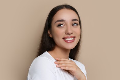 Photo of Portrait of beautiful young woman with elegant makeup on dark beige background