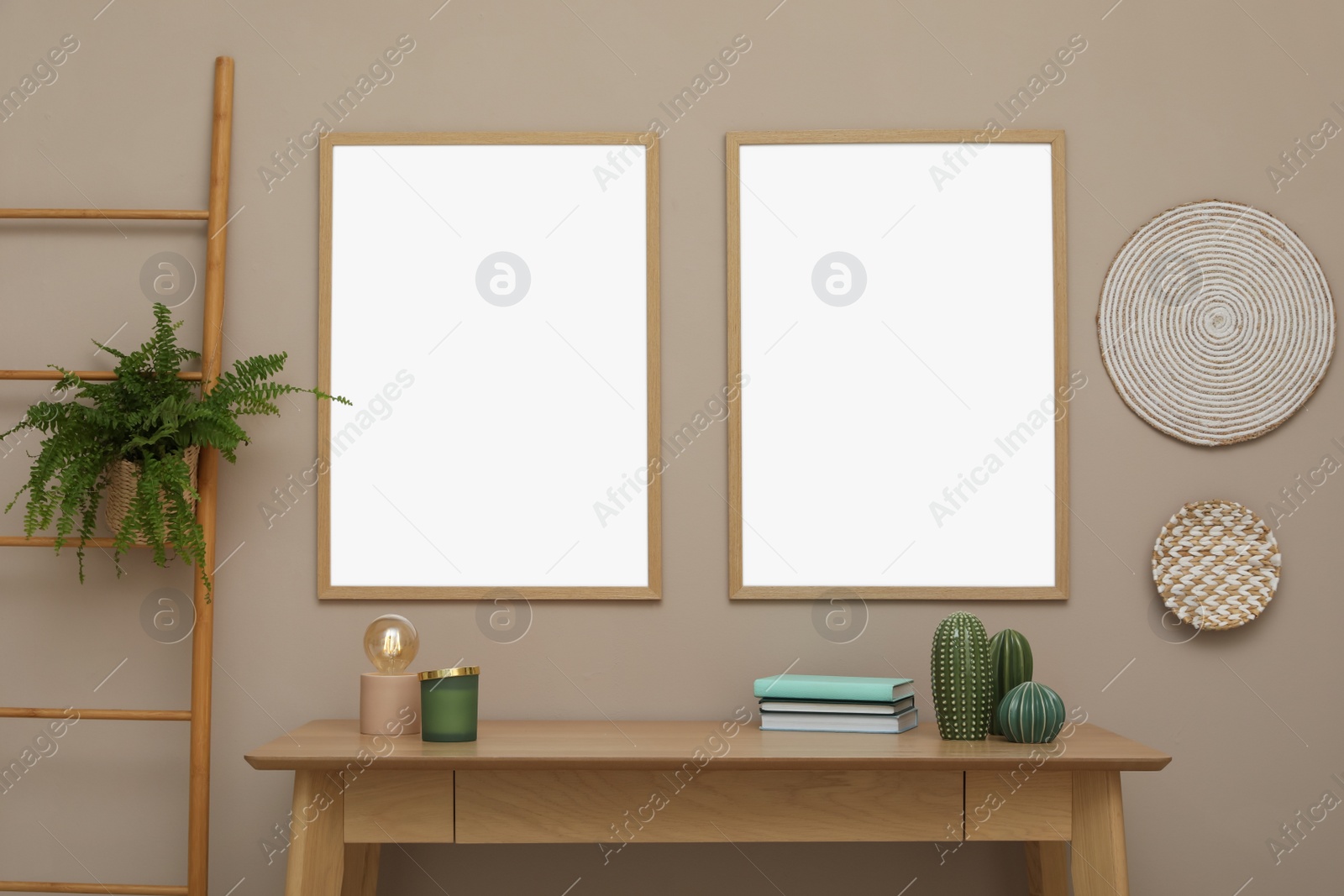 Photo of Empty frames hanging on beige wall over wooden table with decor. Mockup for design