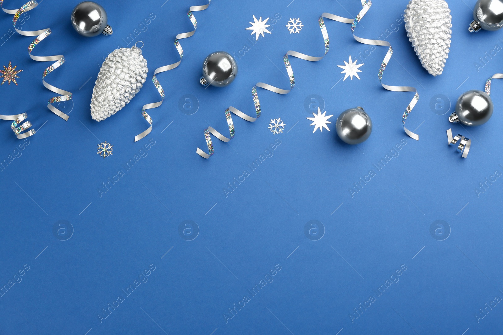 Photo of Flat lay composition with serpentine streamers and Christmas decor on blue background. Space for text