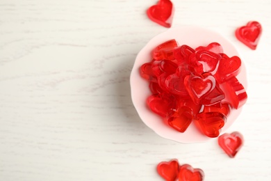 Sweet heart shaped jelly candies on white wooden table, flat lay. Space for text