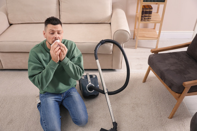 Photo of Man with vacuum cleaner suffering from dust allergy at home