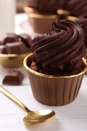 Delicious chocolate cupcake on white wooden table, closeup