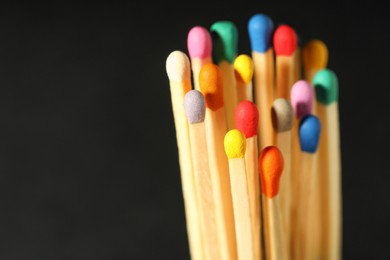 Matches with colorful heads on black background, closeup. Space for text