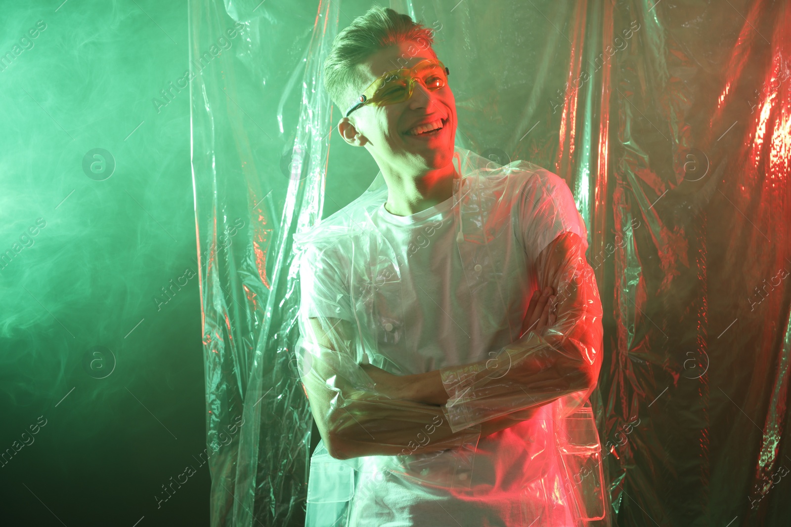 Photo of Stylish young man wearing clear coat and glasses in neon lights