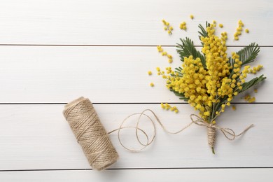 Beautiful mimosa flowers and twine on white wooden table, flat lay