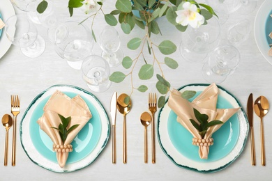 Beautiful table setting with cutlery, glasses, napkins and plates on grey background, top view