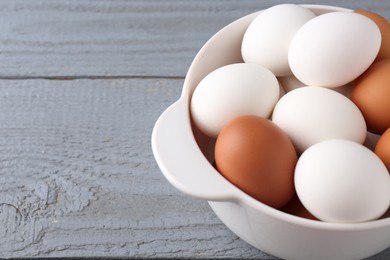Unpeeled boiled eggs in saucepan on grey wooden table, closeup. Space for text