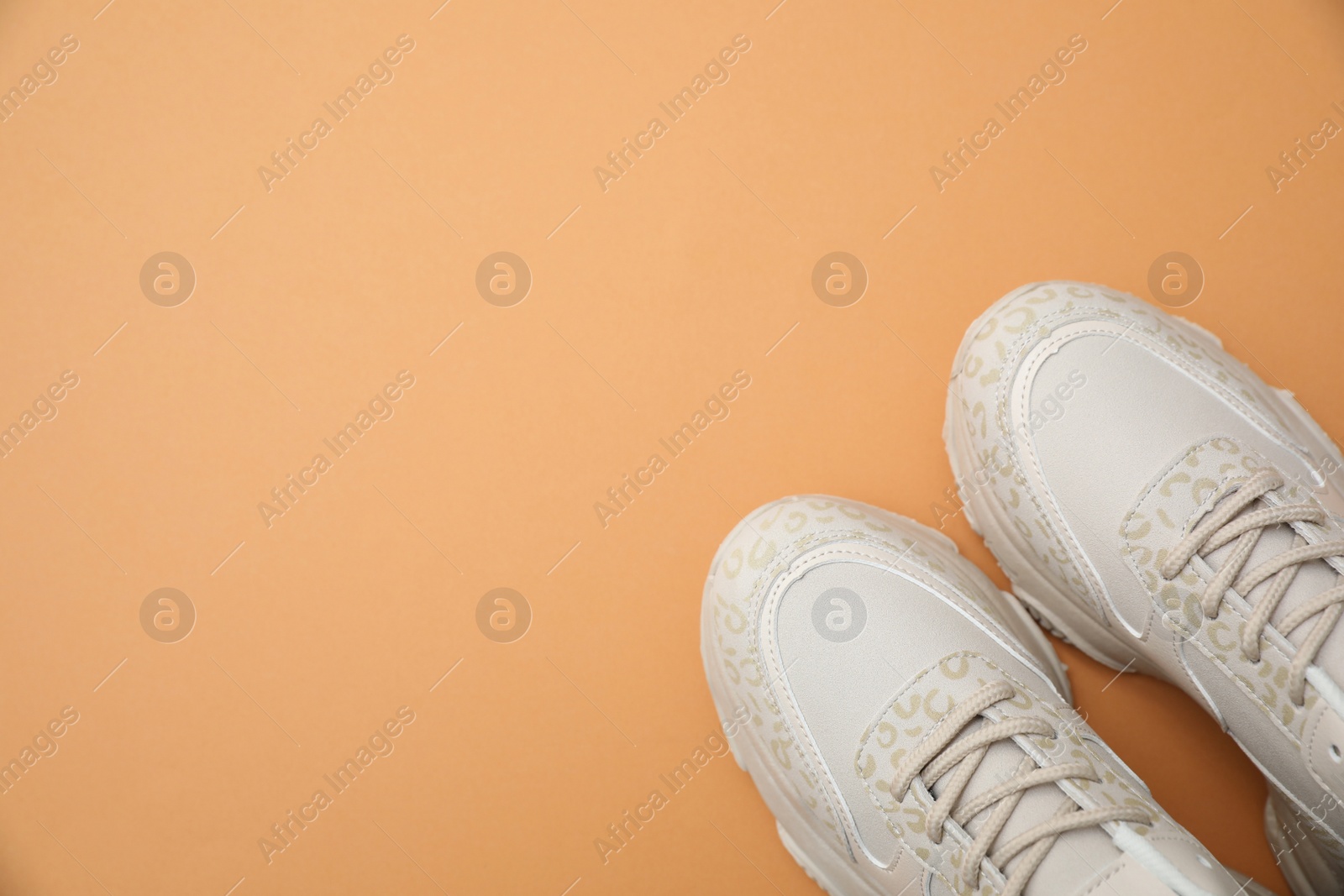 Photo of Stylish women's sneakers on orange background, top view. Space for text