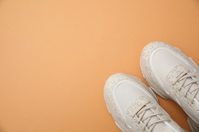 Photo of Stylish women's sneakers on orange background, top view. Space for text